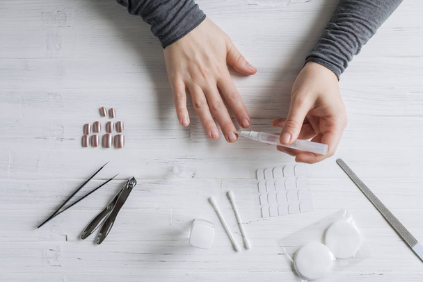 The process of putting artificial (fake) fingernail on the finger. Woman manicure. Flat lay. - Фото, изображение