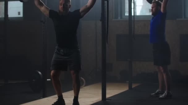 Dos hombre fuerte haciendo ejercicio de barra de arranque en el gimnasio en cámara lenta
 - Imágenes, Vídeo