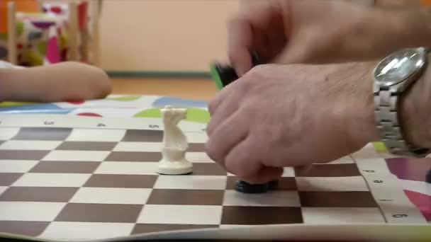 Opettaja opettaa lapsen pelaamaan shakkia. - Materiaali, video