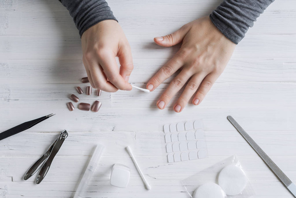 The process of putting artificial (fake) fingernail on the finger. Woman manicure. Flat lay. - Fotó, kép