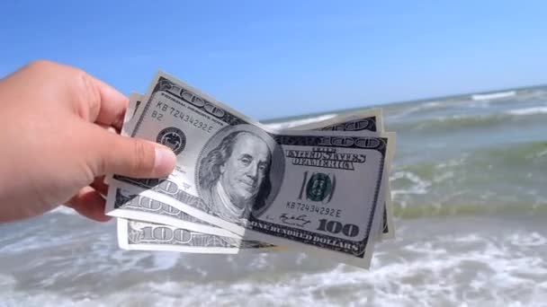 Девушка с деньгами в 300 долларов на фоне океана - Кадры, видео