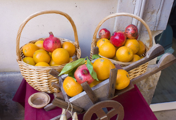 Cestas con naranjas y granadas para hacer jugo fresco en el mercado callejero de Sicilia
 - Foto, Imagen