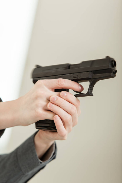 Голые руки, держащие огнестрельное оружие и направляющие в сторону от камеры, готовые стрелять
. - Фото, изображение