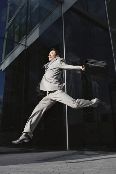 Businessman holding briefcase Jumping - 写真・画像
