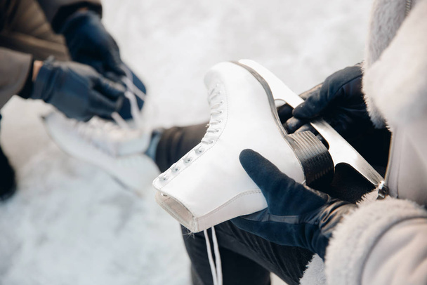 Hombre ayuda a poner en patines para pista de hielo de nieve para niña, concepto de vacaciones de invierno, descanso familiar - Foto, imagen