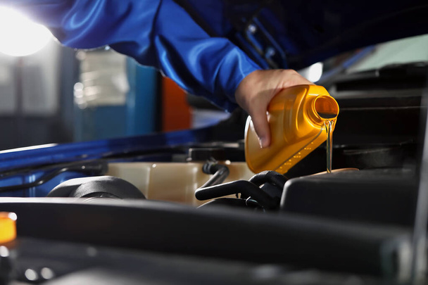 Male mechanic refilling car oil in service center - Photo, Image