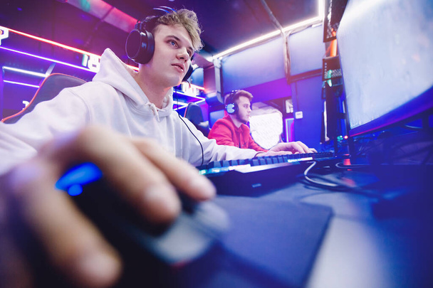 Jugador profesional jugando torneos online videojuegos ordenador con auriculares, rojo y azul - Foto, imagen