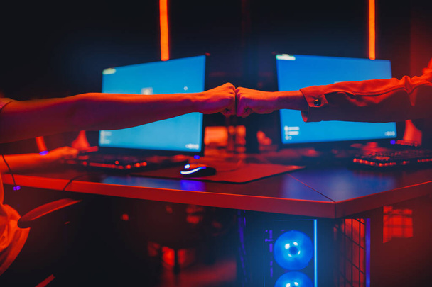 Профессиональный геймер приветствия и поддержки команда кулаки руки онлайн игры в неоновом цвете размытый фон. Мягкий фокус, вид сзади - Фото, изображение