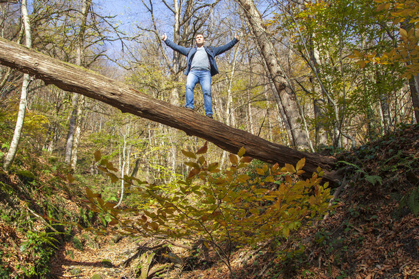 Active leisure, a man stands on a fallen tree through a mountain - Photo, Image