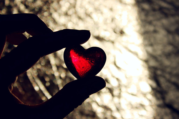 Női kéz kezében egy piros üveg szív, vízszintes nézet. Szerelem, Valentin nap koncepció.  - Fotó, kép