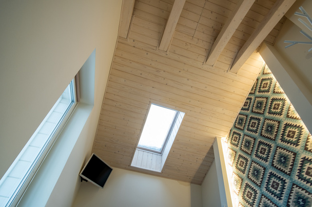 Деревянный потолок в современном мансардном номере с мансардным окном
  - Фото, изображение