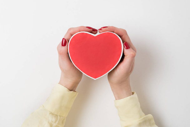 Vintage style red heart shaped box in female hand isolated on white background - Photo, Image