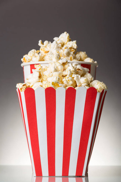 Two striped boxes filled with popcorn on gray background. - 写真・画像