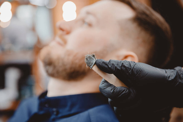 Friseurmeister entfernt Haare aus der Nase des Mannes mit Wachs, Enthaarung Schönheitsoperation - Foto, Bild