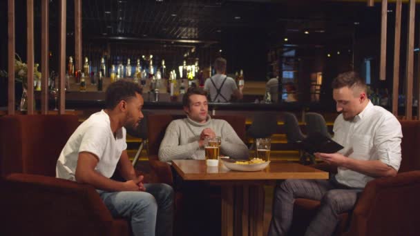 Freunde sitzen an der Bar, sie legen Geld in einen Schein nach dem anderen - Filmmaterial, Video