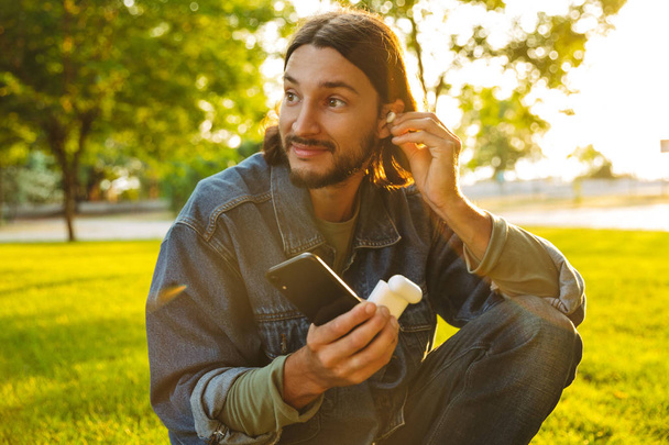 Smiling young man holding mobile phone - Fotoğraf, Görsel