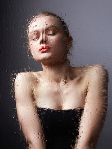 hermosa chica detrás de vidrio mojado. mujer en el baño
 - Foto, Imagen