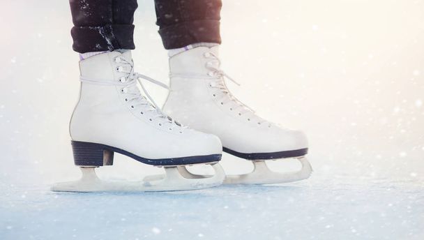 A lány jégen áll fehér műkorcsolyában, hópelyhekben. Téli aktív nyaralás koncepciója - Fotó, kép
