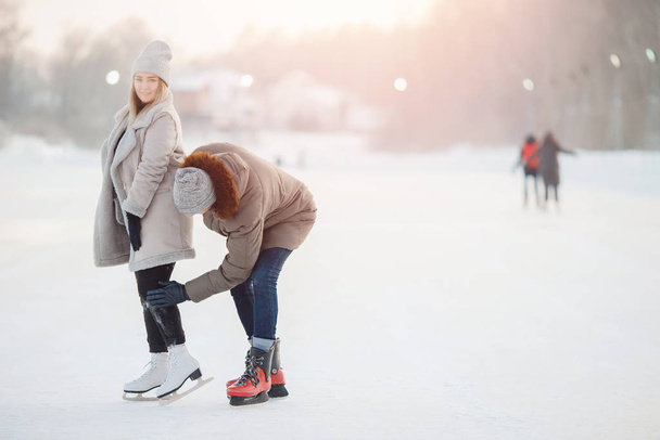 Man helps and shakes girl from snow after falling at ice rink in winter. Concept care and love of couple - Foto, Imagem