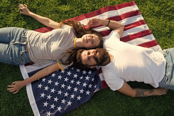History of America. American patriotic people. American couple relaxing on USA flag outdoors. Independence day. National holiday. Bearded hipster and girl in love. 4th of July. American tradition - Photo, Image