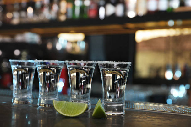 Mexican Tequila shots with lime slices on bar counter - Фото, изображение