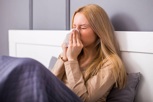 Exhausted woman having fever and blowing nose. - Photo, Image