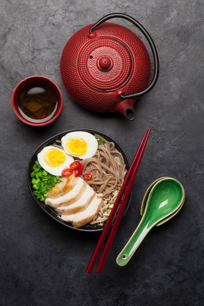 Ázsiai tészta ramen leves csirke, zöldség és tojás és gyógynövény tea kő alapon. Top view lapos fektetés - Fotó, kép