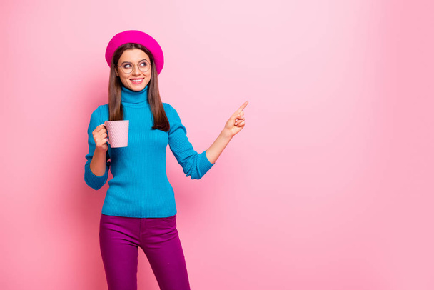 Portrait of positive french girl travel trip point index finger copy space show cafe cafeteria sales promotion hold cup latte ads wear blue trousers isolated over pink color background - Φωτογραφία, εικόνα