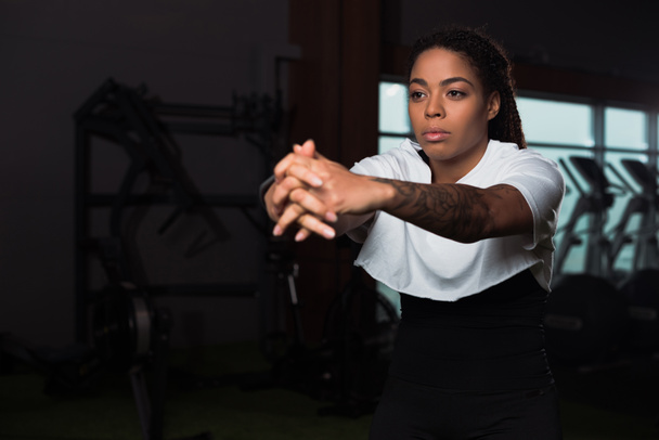 Selective focus of african american attractive woman clenching hands and training in gym - Photo, Image