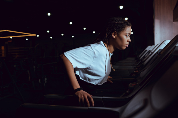 Side view of african american woman running on treadmill in gym - Photo, Image