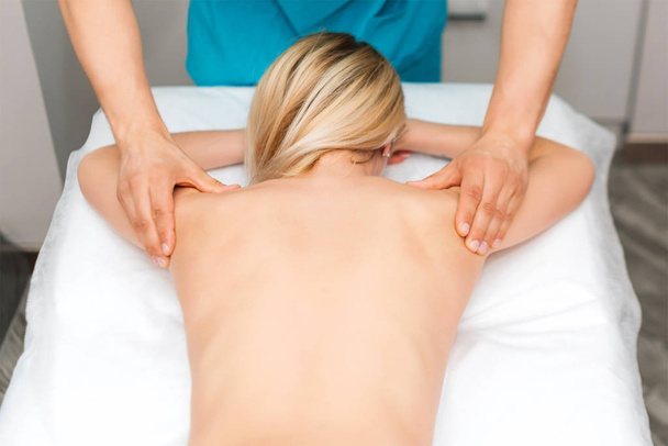 Handen van een massagetherapeut die rugmassage van een vrouw doet. Jonge vrouw met een lichaam beeldhouwprocedure. chiropractie in de rug. Osteopathie, alternatieve geneeskunde, pijn verlichting concept. - Foto, afbeelding