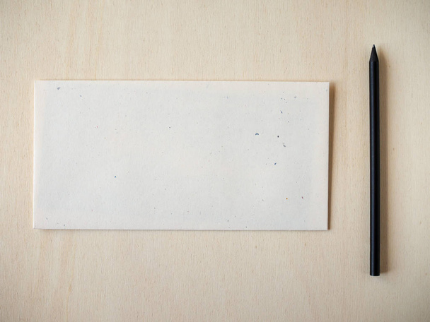 Пустое письмо на деревянном столе с черным карандашом - плоский
 - Фото, изображение
