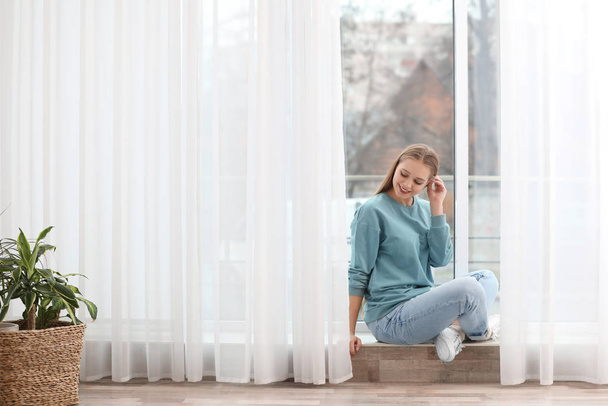 Beautiful young woman near window at home - Valokuva, kuva