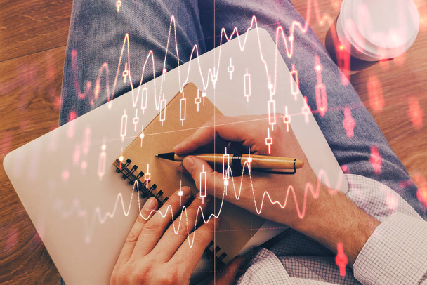 Double exposure of hands writing in notepad with stock market chart. - Fotó, kép