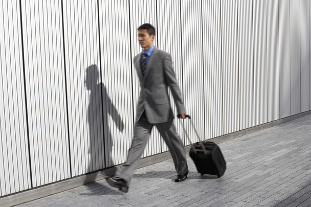 Businessman walking pulling suitcas - Foto, afbeelding