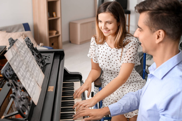Fiatal nő tolószékben tanít férfi zongorázni - Fotó, kép