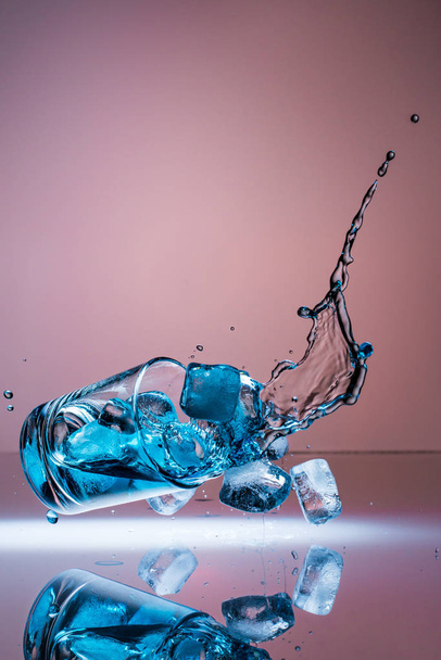 a glass with blue liquid falls down and injected elegantly into the air. - 写真・画像