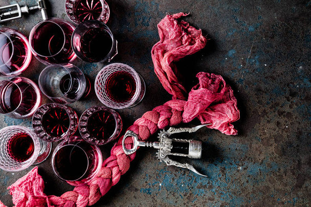 top view of glasses of red wine and corkscrews on grey surface - Фото, зображення