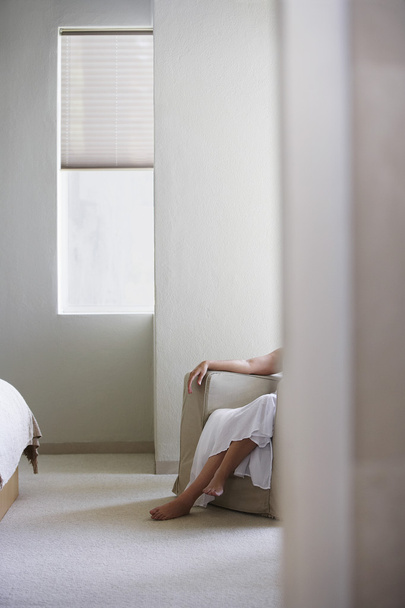 Woman sitting on armchair in bedroom - Fotoğraf, Görsel
