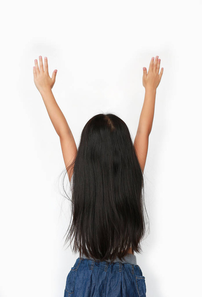 Little Asian child girl raising hands up isolated over white background. Rear view. - 写真・画像