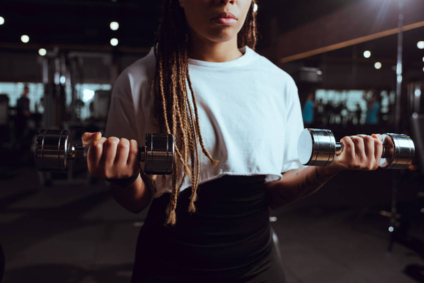 Vista recortada de mujer afroamericana levantando pesas
 - Foto, imagen