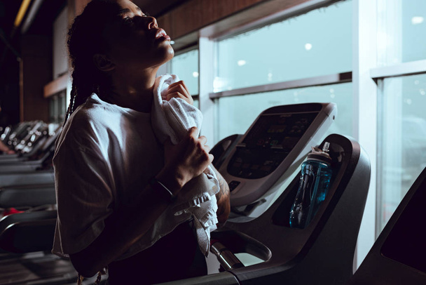 Attractive african american woman using towel after runnin on treadmill - Photo, Image