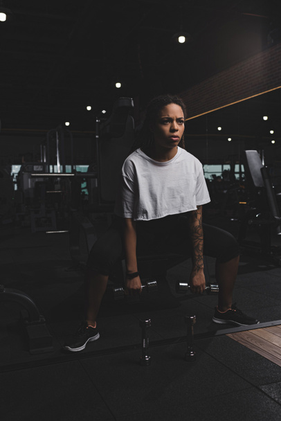 Femme afro-américaine accroupie avec haltères dans la salle de gym
 - Photo, image