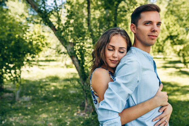 Beautiful couple in love dating outdoors at the park on a sunny day. Happy couple in love embracing each other, looking with love having eyes full of happiness. Date day. Family time - Foto, Imagen