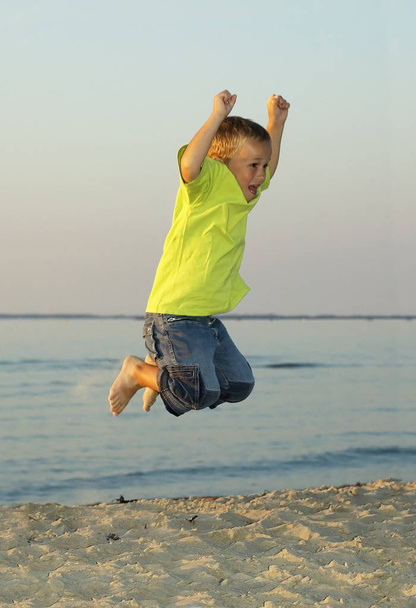 Jumping 6 year old on a beach during sunset. - Photo, image