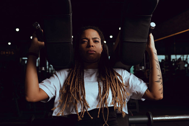 getatoeëerd Afrikaans amerikaanse vrouw uit te werken op fitness apparaat - Foto, afbeelding