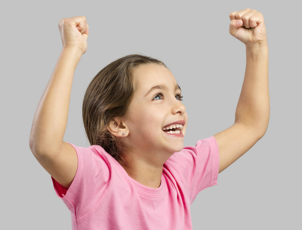 Studio portrait of a happy little girl with arms raised on air - Fotó, kép