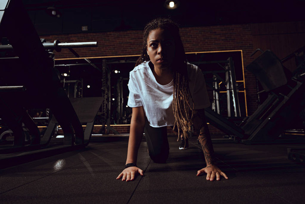 attractive african american woman with dreadlocks doing plank exercise in gym  - Φωτογραφία, εικόνα