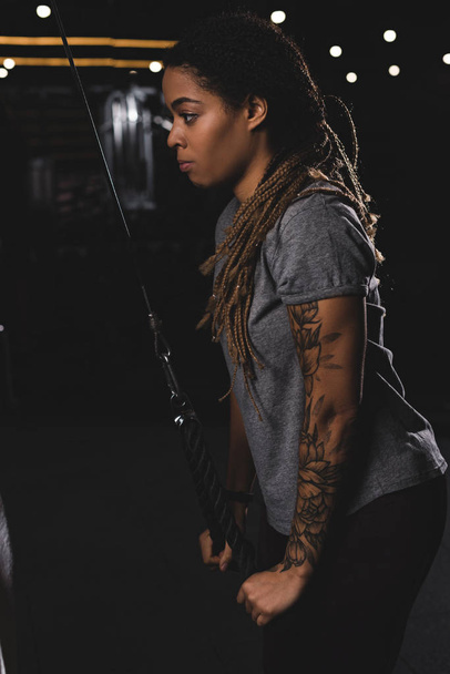 vista laterale della ragazza afroamericana con tatuaggio che si esercita in palestra
  - Foto, immagini