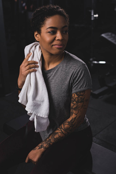 happy african american girl holding towel and smiling in gym  - Fotoğraf, Görsel